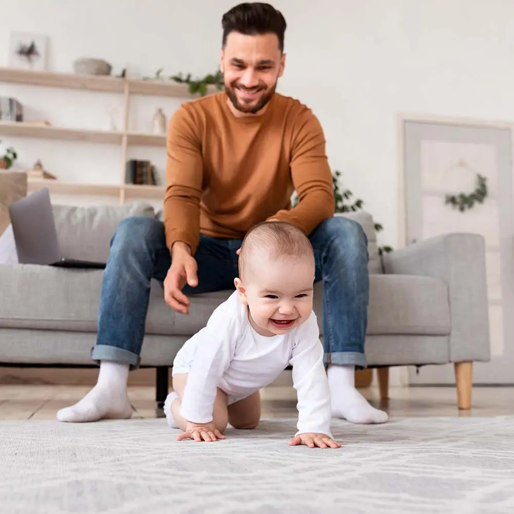 happy daddy looking at baby crawling on floor at h VUE57SM